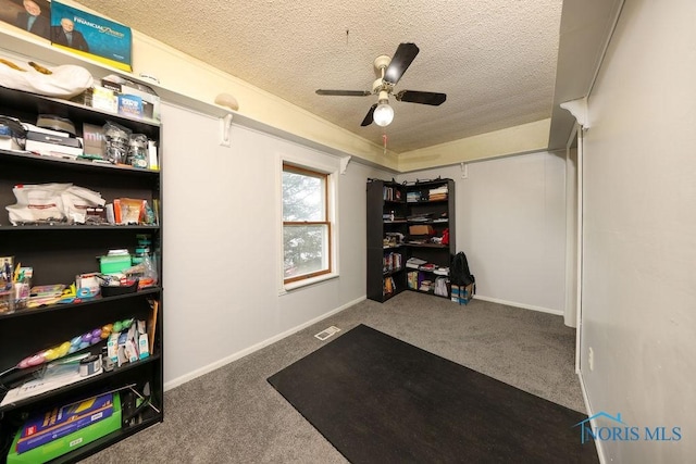 interior space featuring ceiling fan, dark carpet, and a textured ceiling