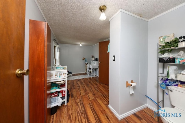 hall featuring a textured ceiling, wood-type flooring, and ornamental molding