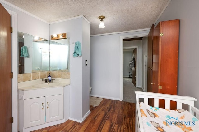 bathroom with vanity, a textured ceiling, crown molding, wood-type flooring, and toilet