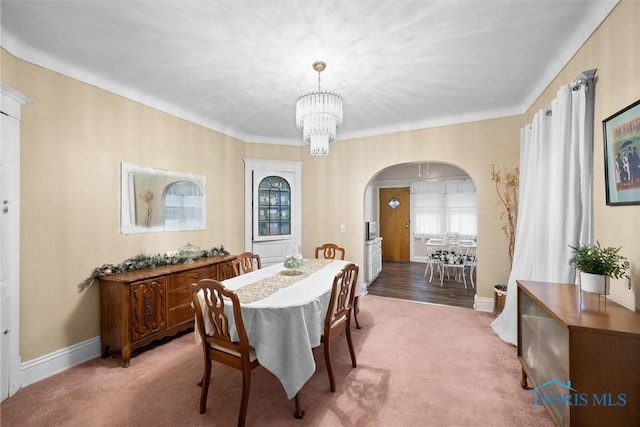 carpeted dining space featuring a notable chandelier