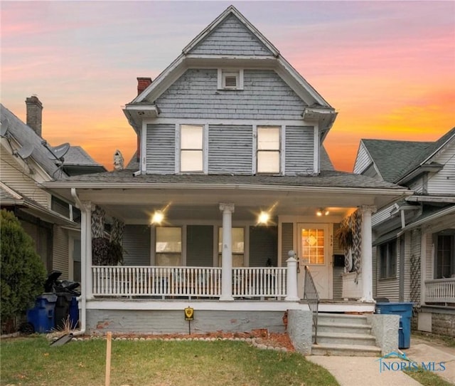 view of front facade featuring covered porch and a yard