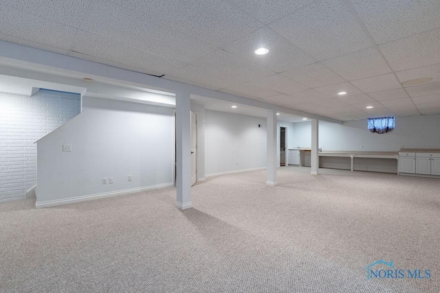 basement with a paneled ceiling and carpet flooring