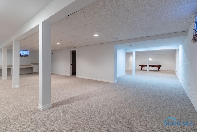 basement featuring a drop ceiling and light colored carpet