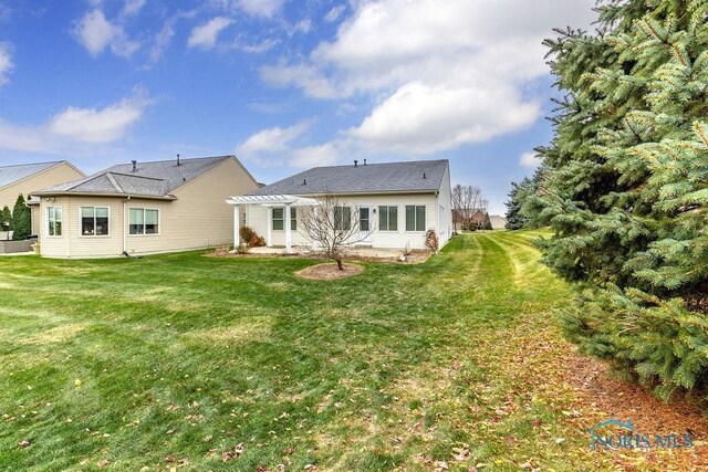 back of property with a yard and a pergola