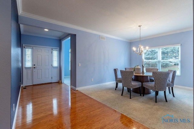 dining room featuring crown molding, wood-type flooring, and a chandelier