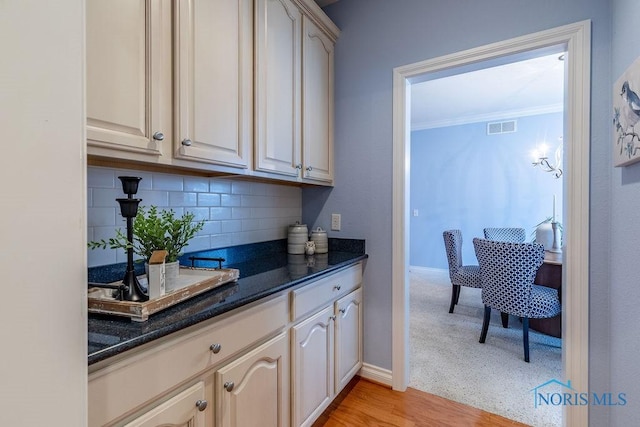 kitchen featuring crown molding, dark stone countertops, and decorative backsplash