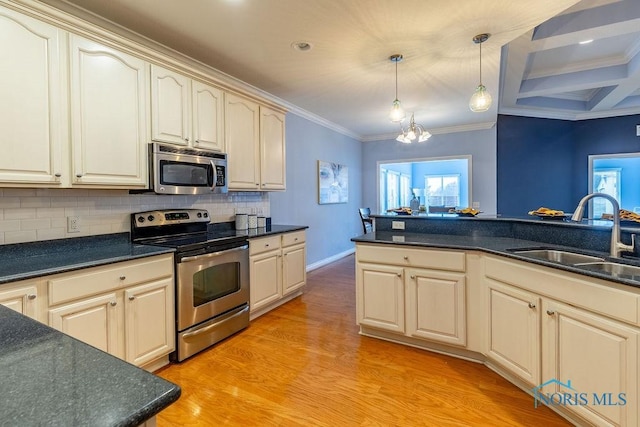 kitchen featuring sink, hanging light fixtures, stainless steel appliances, light hardwood / wood-style floors, and cream cabinetry