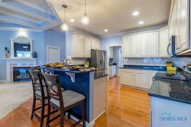 kitchen with crown molding, light hardwood / wood-style flooring, hanging light fixtures, appliances with stainless steel finishes, and backsplash