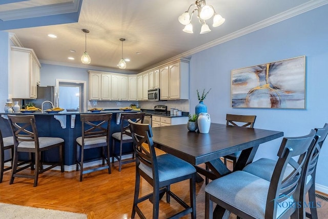 dining area featuring crown molding, an inviting chandelier, and light wood-type flooring