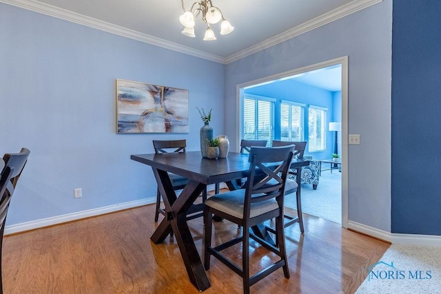 dining room with ornamental molding, wood-type flooring, and a chandelier