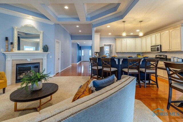 living room featuring coffered ceiling, crown molding, and wood-type flooring