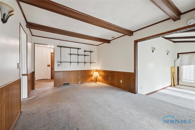 unfurnished room with light carpet, beam ceiling, crown molding, and wooden walls