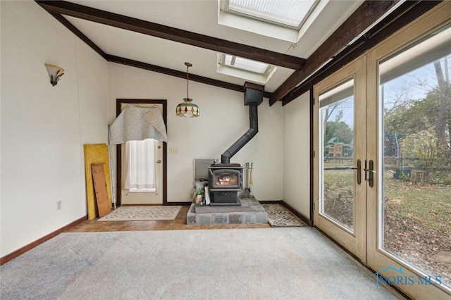 carpeted foyer entrance featuring french doors, a wood stove, and vaulted ceiling with skylight