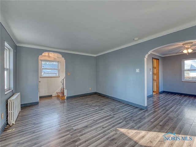 unfurnished room featuring crown molding, ceiling fan, radiator heating unit, and dark wood-type flooring