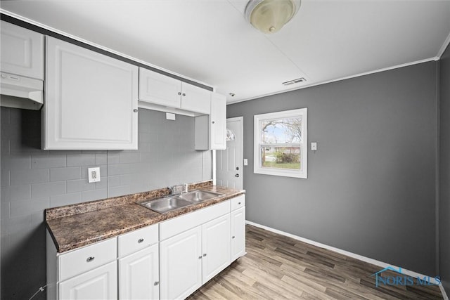 kitchen featuring tasteful backsplash, sink, white cabinets, and light hardwood / wood-style floors