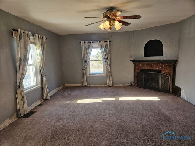 unfurnished living room with plenty of natural light, ceiling fan, carpet floors, and a fireplace