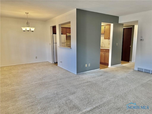 empty room featuring light colored carpet and a notable chandelier