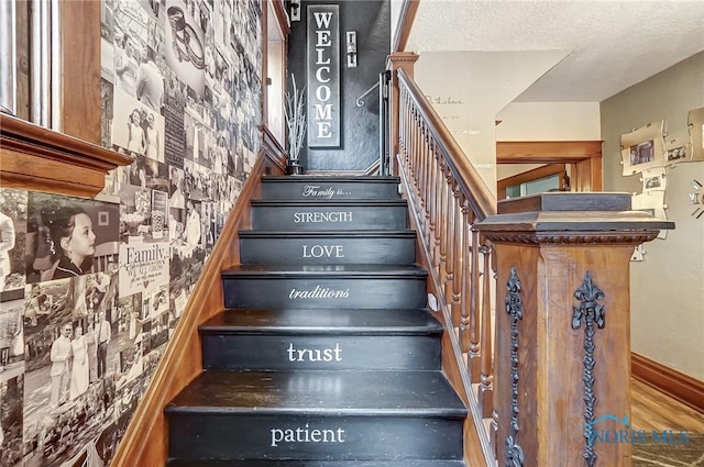 stairway with hardwood / wood-style floors and a textured ceiling