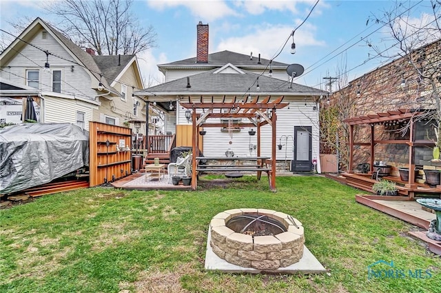 rear view of property with a pergola, a fire pit, a lawn, and a wooden deck