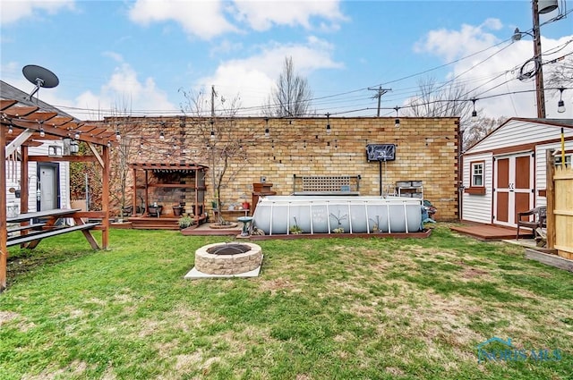 view of yard with a swimming pool side deck, a shed, and an outdoor fire pit