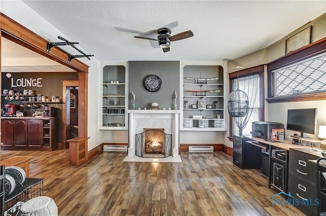 living room featuring hardwood / wood-style floors, a textured ceiling, ceiling fan, and a premium fireplace