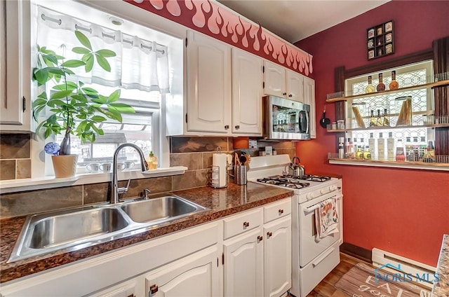 kitchen featuring a wealth of natural light, white gas stove, and white cabinets