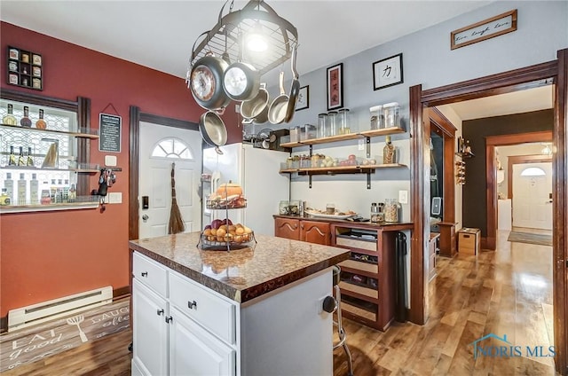 kitchen featuring a baseboard heating unit, a center island, light hardwood / wood-style floors, white cabinetry, and white fridge with ice dispenser