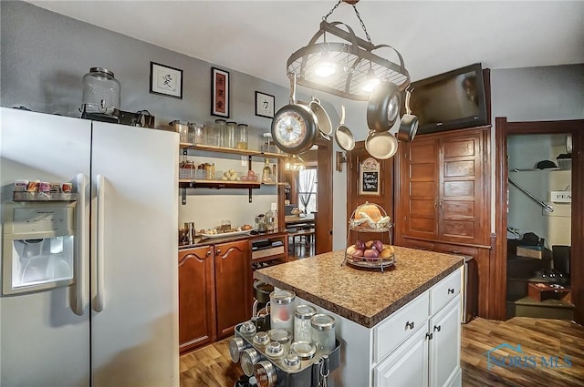 kitchen with light wood-type flooring, a center island, white cabinetry, and white fridge with ice dispenser