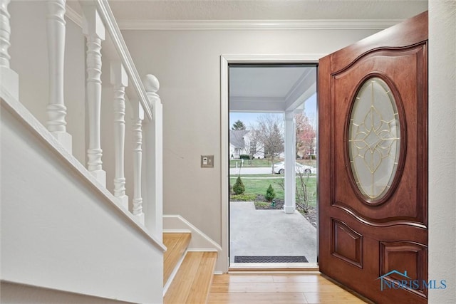 foyer entrance with light hardwood / wood-style flooring and crown molding