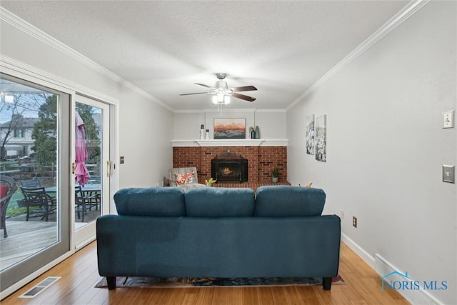 living room featuring hardwood / wood-style flooring, ceiling fan, ornamental molding, and a textured ceiling