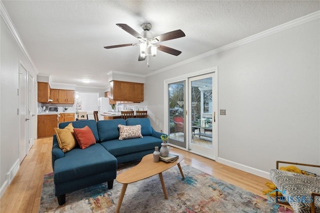 living room with ceiling fan, light hardwood / wood-style floors, ornamental molding, and a textured ceiling