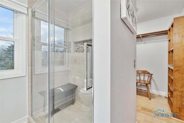 bathroom with hardwood / wood-style flooring, plenty of natural light, and a shower with shower door