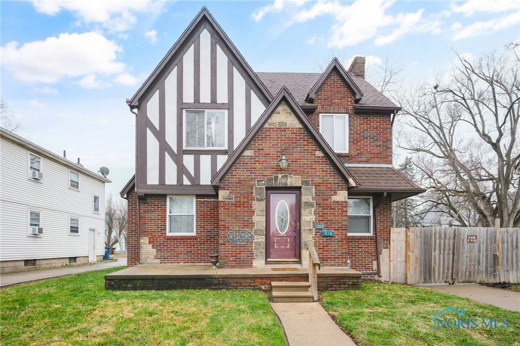 english style home with a patio and a front lawn