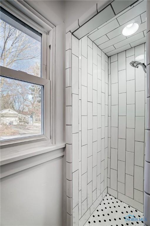 bathroom with tiled shower and a healthy amount of sunlight