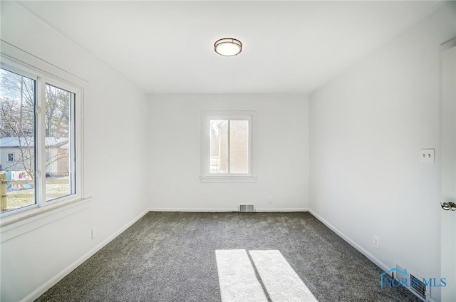 unfurnished room with plenty of natural light and dark carpet