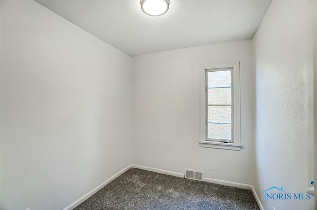 spare room with dark carpet