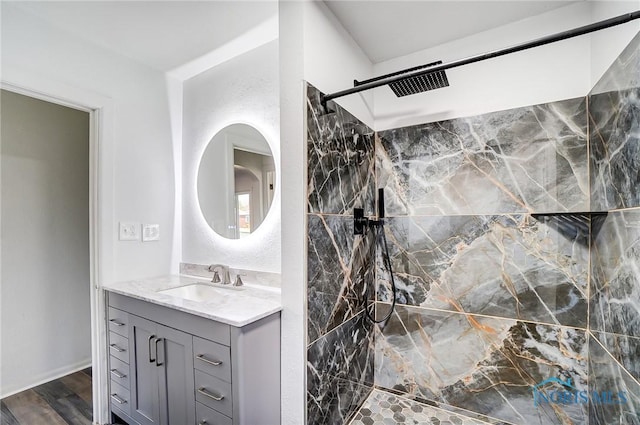 bathroom with hardwood / wood-style floors, vanity, and a tile shower