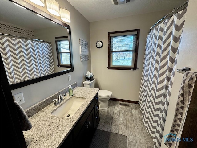 bathroom with toilet, hardwood / wood-style flooring, vanity, and walk in shower