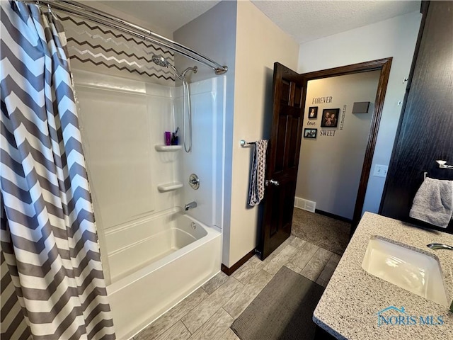 bathroom with a textured ceiling, shower / bath combo with shower curtain, and vanity