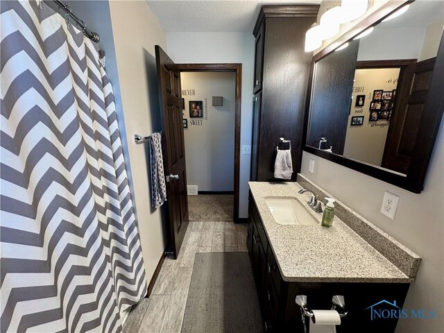 bathroom with hardwood / wood-style floors, vanity, and a textured ceiling