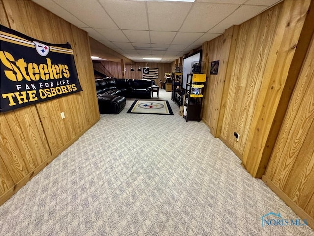 hallway featuring a paneled ceiling and wood walls