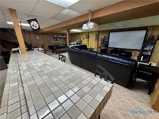 carpeted cinema featuring a paneled ceiling and wood walls