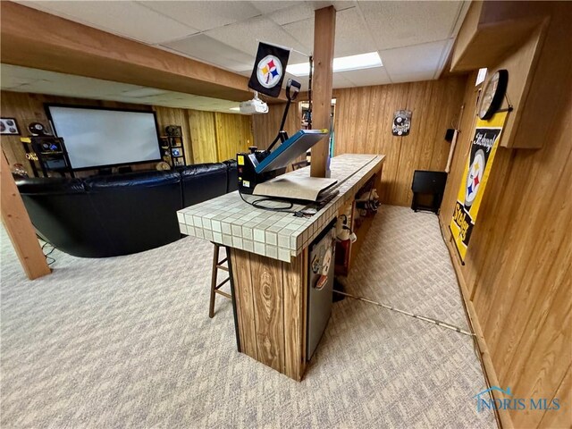 game room with light carpet, a drop ceiling, and wood walls