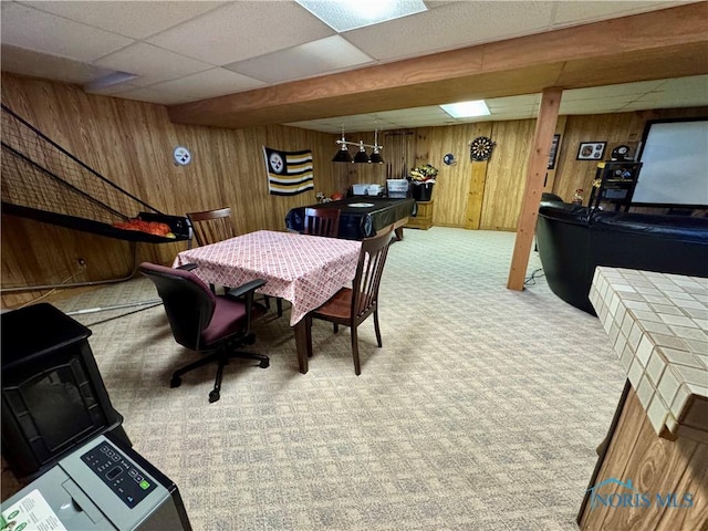 dining room featuring a paneled ceiling, carpet, and wood walls