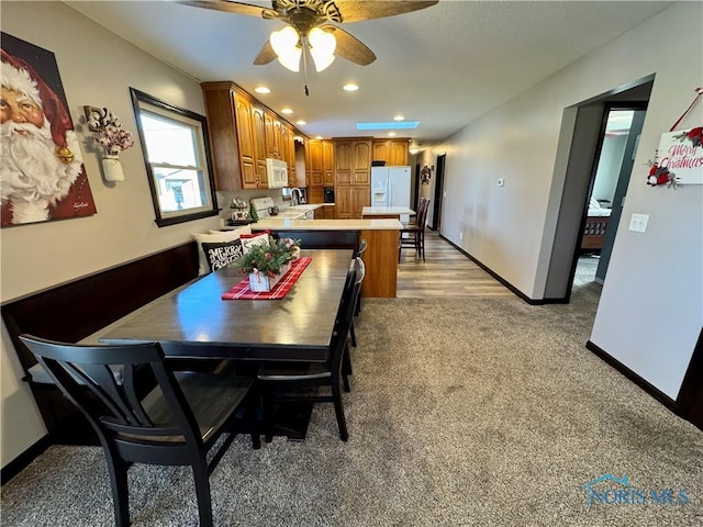 dining space featuring light carpet and ceiling fan