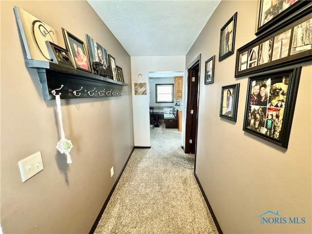 hall featuring a textured ceiling and light carpet