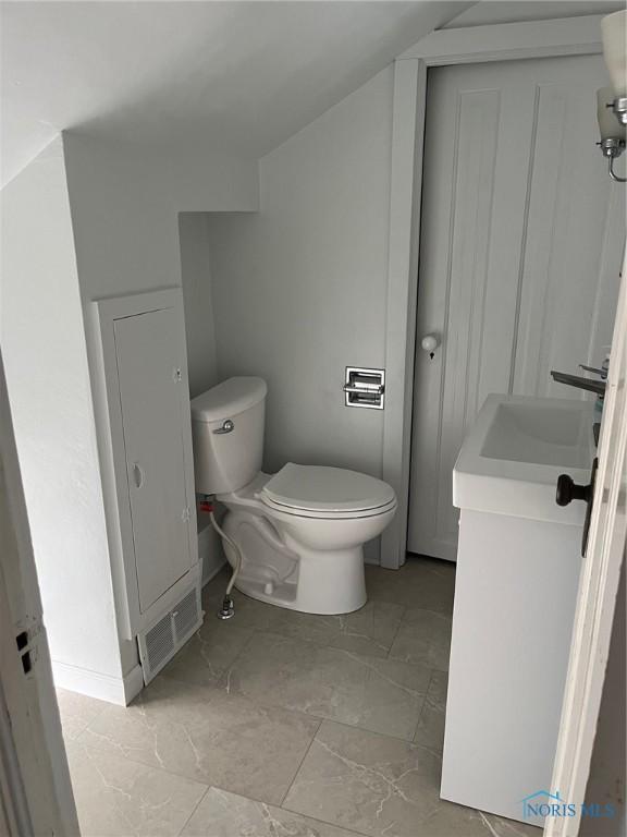 bathroom featuring vanity, vaulted ceiling, and toilet