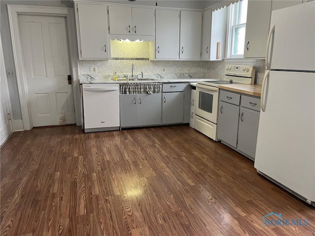 kitchen featuring white appliances, backsplash, white cabinets, sink, and dark hardwood / wood-style floors