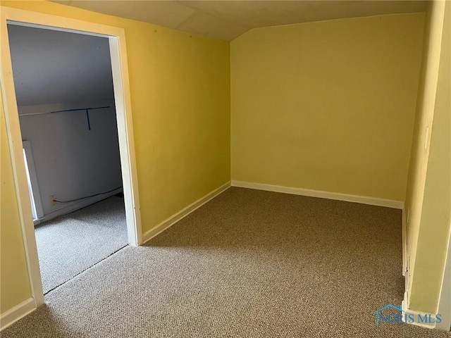 spare room with carpet flooring and vaulted ceiling