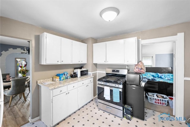 kitchen with light wood-type flooring, white cabinetry, and stainless steel range with gas stovetop